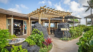 A restaurant with a wooden pergola, outdoor seating, and a view of the ocean. - Waipouli Beach Resort A106 Oceanfront 2BD 3BA (Kapaʻa)