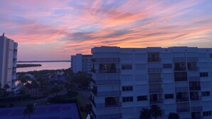Un immeuble de grande hauteur doté de nombreux balcons, offrant une vue dégagée sur les environs et un ciel au coucher du soleil.