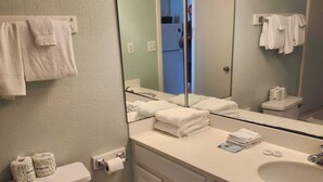 A bathroom with a toilet, sink, mirror, and towels. - Sea Mist 51508 (Myrtle Beach)
