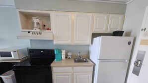 A compact kitchen with white cabinets, a black stove, a white refrigerator, a microwave, and a sink. - Sea Mist 51508 (Myrtle Beach)