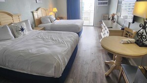 A hotel room with two beds, a small table, a chair, a desk, a mirror, and a view of the outside. - Sea Mist 51508 (Myrtle Beach)