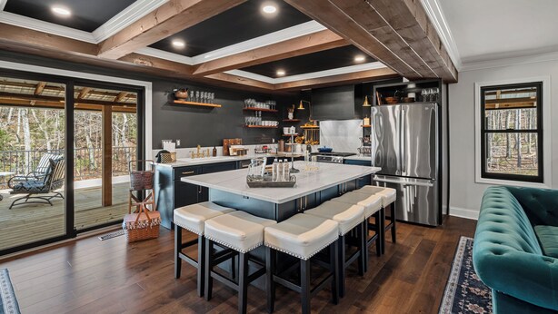 A modern kitchen with a large island, stainless steel appliances, and a view to the outside.