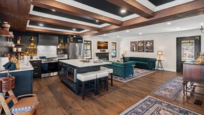 A modern kitchen with a central island, dark cabinetry, and wooden beams on the ceiling.