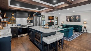 A modern kitchen with dark cabinetry, stainless steel appliances, and a central island with stools.