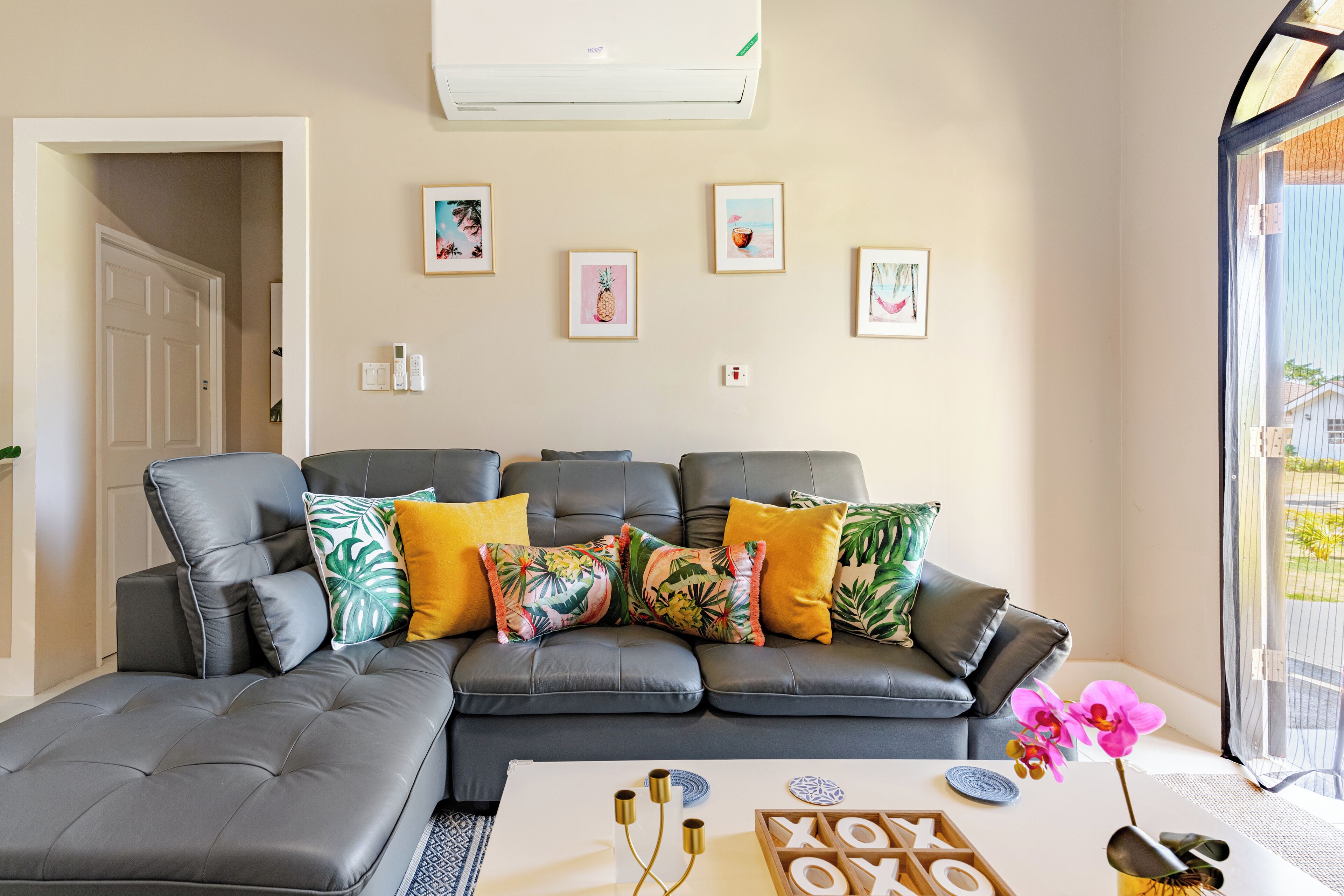 Una sala moderna con un sofá seccional gris, una mesa de centro con objetos decorativos y cuadros en la pared.