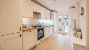 Une cuisine moderne avec des meubles blancs, une cuisinière à gaz et un four encastré.