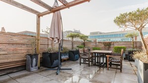 An outdoor patio with a wooden pergola, a table with chairs, and potted plants. - Airy S Kensington 2BR w/ Doorman & Balcony, nr Museums, by Blueground (London)