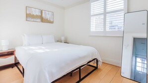 A bedroom with a bed, bedside tables, a window with blinds, and a mirror. - Airy S Kensington 2BR w/ Doorman & Balcony, nr Museums, by Blueground (London)
