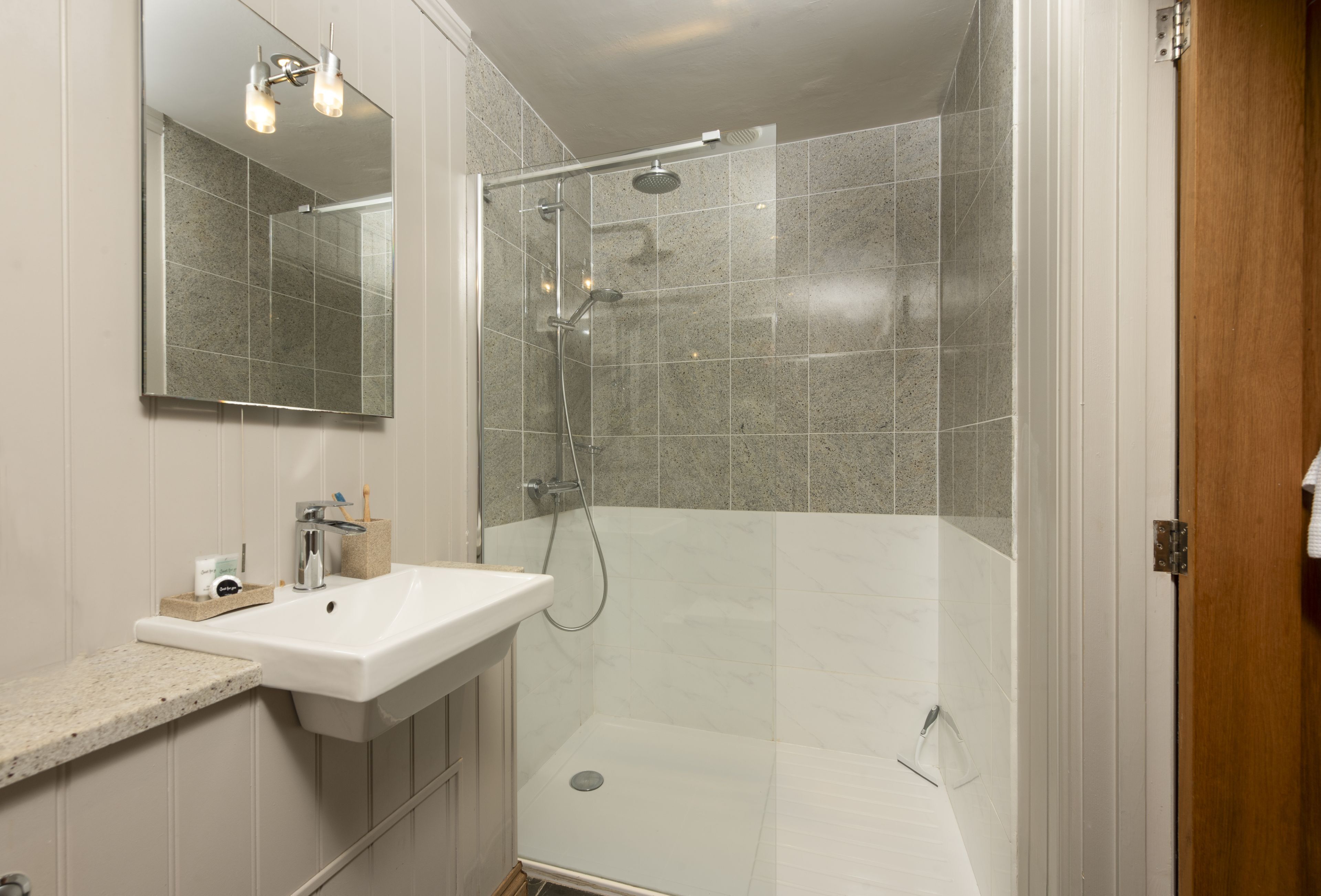 A modern bathroom with a glass-enclosed shower, a white sink, and a mirror above it.