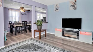 A living room with a fireplace, a TV, and a dining area with a table and chairs.