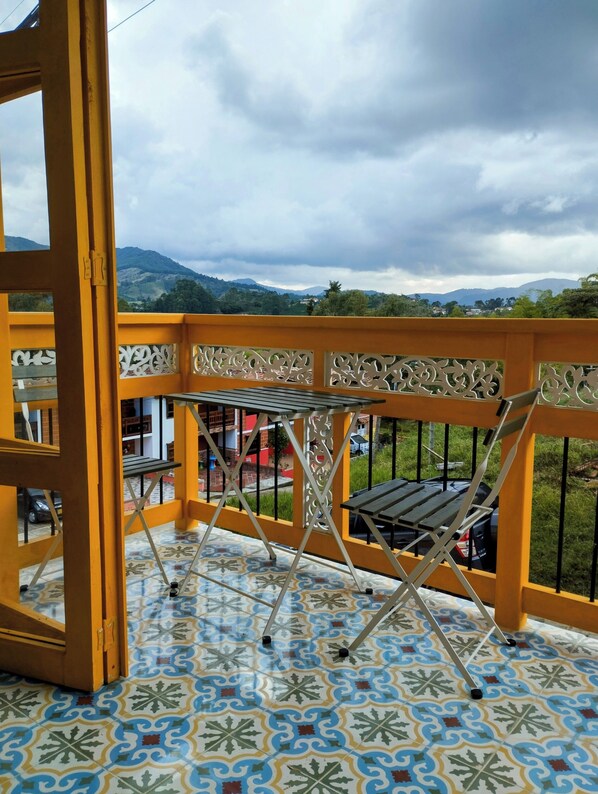 A balcony with a patterned floor, a table, and a chair.