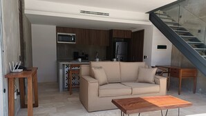 A modern living room with a sofa, a coffee table, and a staircase. - New, Modern Loft in Main Avenue Tulum (Tulum)
