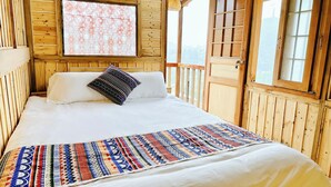 Een houten kamer met een bed, een gebloemd plaid en uitzicht door het raam.