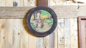 Een houten wand met een ronde afbeelding van twee personen in traditionele kledij.