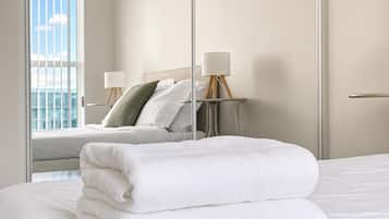 Een hotelkamer met een bed, een nachtkastje met een lamp en uitzicht op de stad.