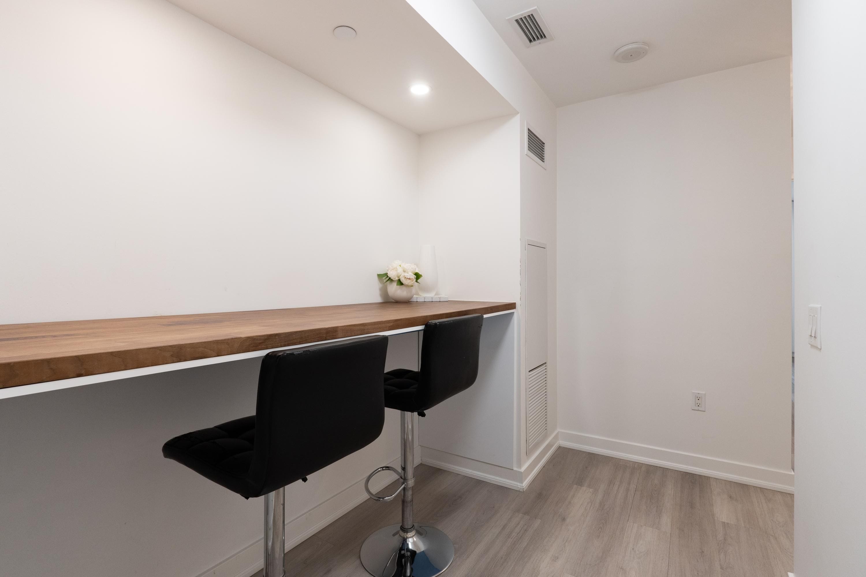 A modern bar area with a wooden countertop and two black barstools.