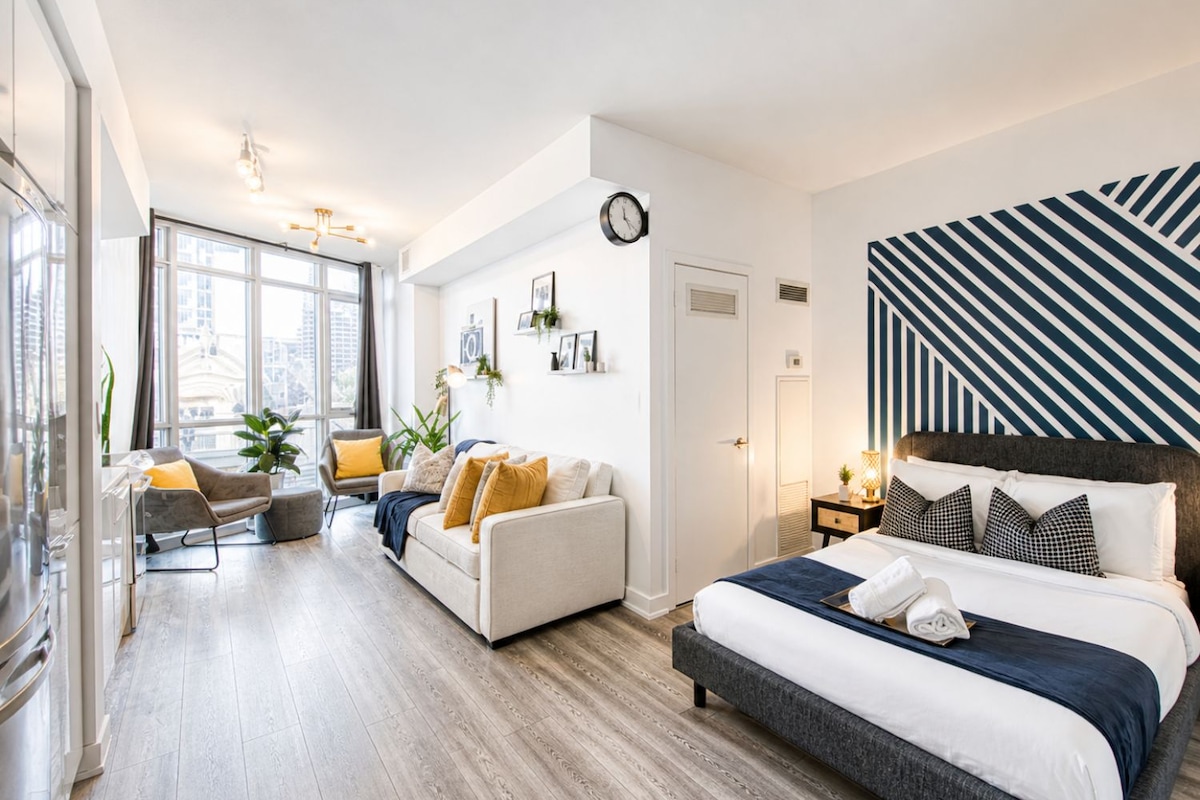 A modern bedroom with a large bed, a sofa, and a dining area.