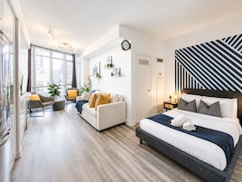 Un dormitorio moderno con una cama grande, un sofá y un comedor.