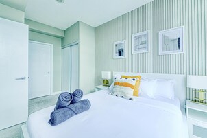 Een hotelkamer met een bed, een nachtkastje, een lamp en een wand met verticale lijnen.