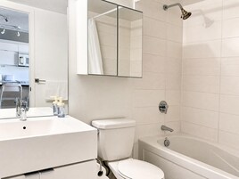 Een moderne badkamer met een wit wastafelmeubel, toilet en bad.