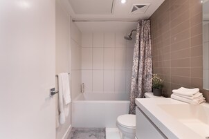 Een moderne badkamer met een douche, toilet en wastafel met handdoeken.