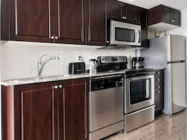 Una cocina moderna con armarios de madera oscura, electrodomésticos de acero inoxidable y encimera de granito.
