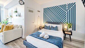 A modern bedroom with a large bed, a sofa, and a wall with geometric patterns. - Panorama Suites-Fort York (Toronto)