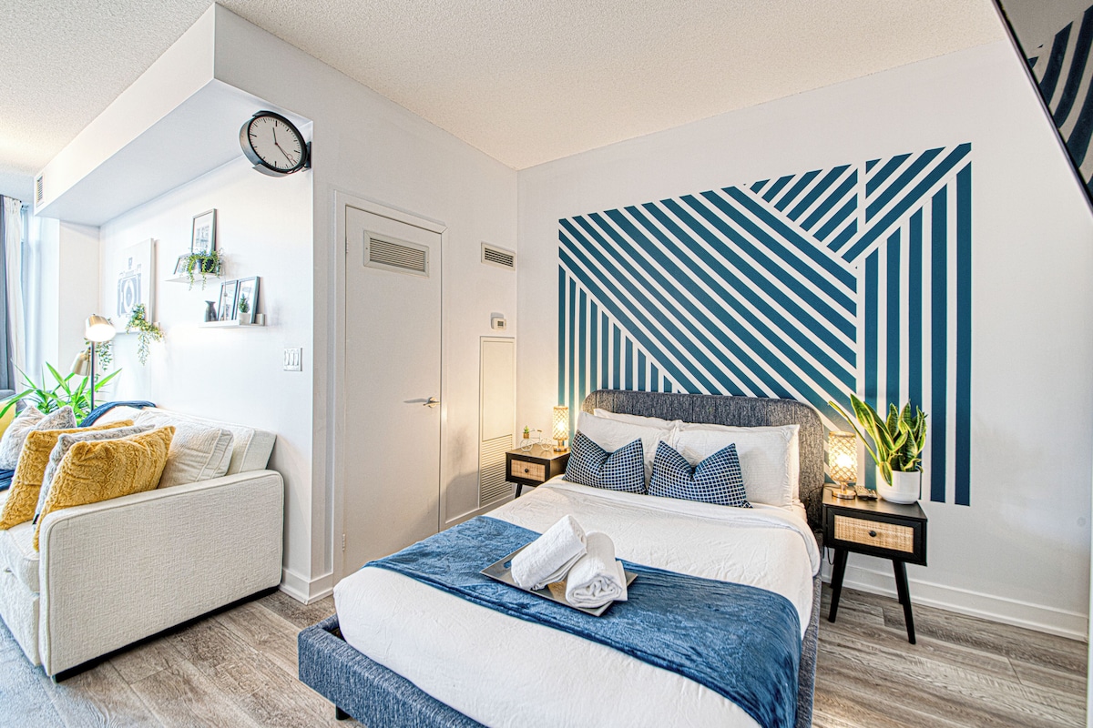 Ett modernt sovrum med en stor säng, en soffa och en vägg med geometriska mönster.