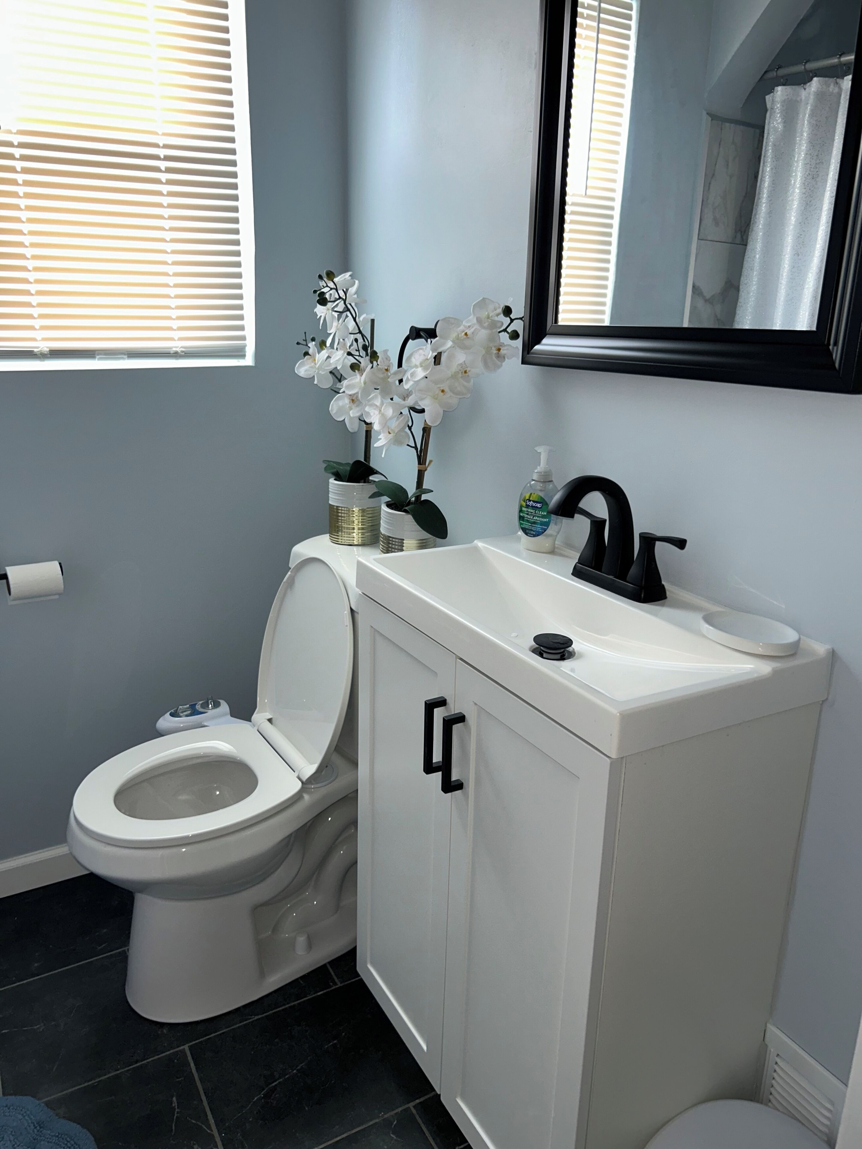 A bathroom with a toilet, a sink, and a mirror.