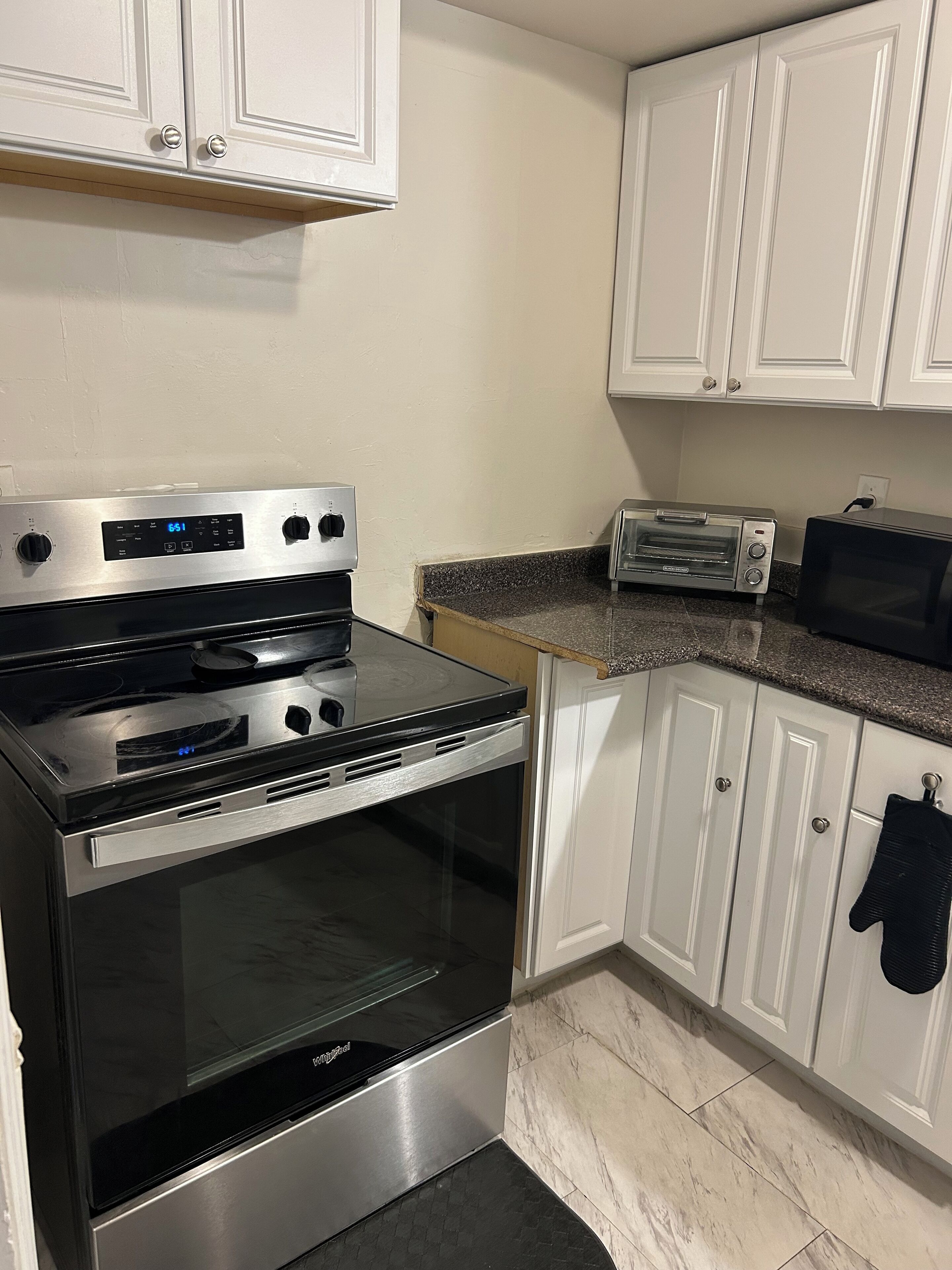 A kitchen with a stainless steel oven, a toaster, and white cabinets.