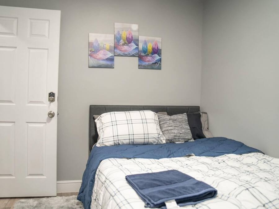 A bedroom with a bed, a door, and three wall-mounted paintings.