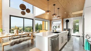 Une cuisine moderne dotée d’un îlot central, de grandes fenêtres et offrant une vue sur l’extérieur.