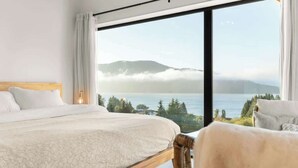Une chambre avec une grande fenêtre donnant sur un lac et des montagnes.