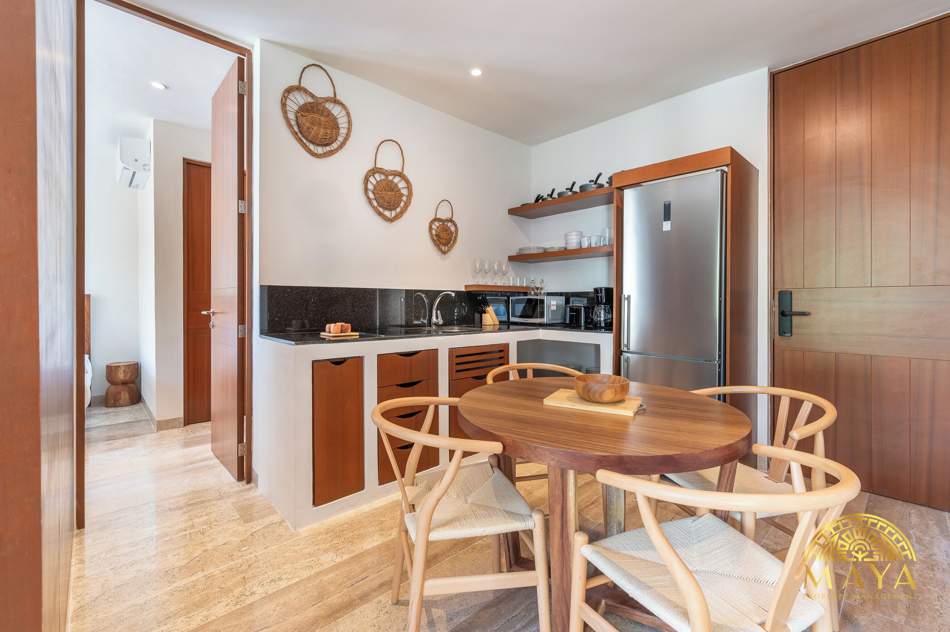 A modern kitchen with wooden cabinets, a round dining table, and wicker wall decorations.