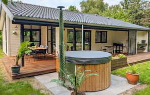 Una casa moderna con un porche cubierto, un jacuzzi y una terraza.