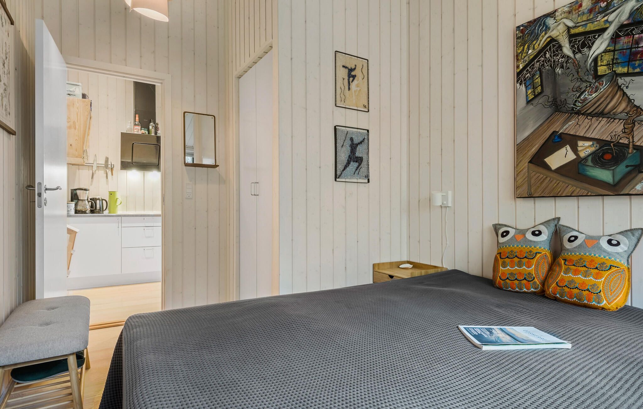 Ein Schlafzimmer mit Bett, einer Bank und einer Wand mit Kunstwerken.