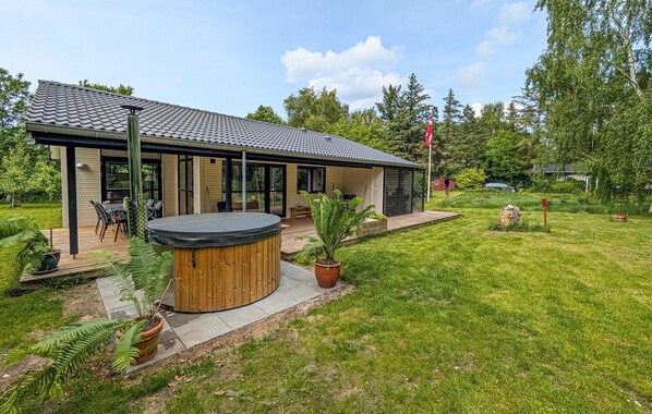 Una casa moderna con patio, jacuzzi y césped bien cuidado.