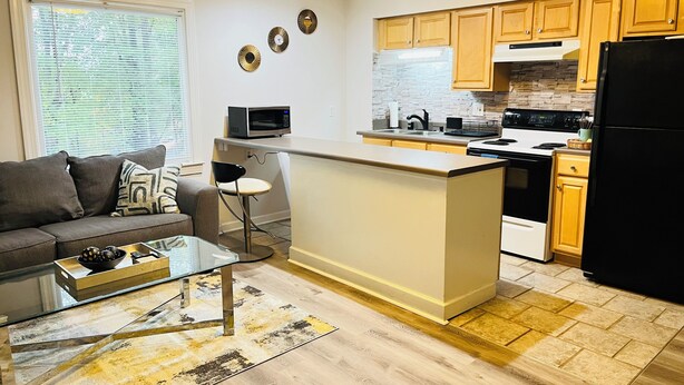 A compact living space with a kitchenette, a sofa, a coffee table, and a small bar stool. - Spacious 2-bedroom, 1 bathroom Basement Apartment near Braves Stadium (Marietta)