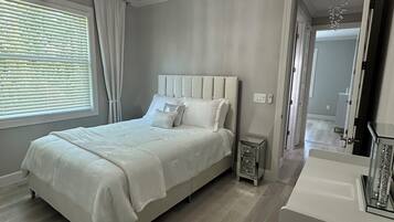 A bedroom with a large bed, a nightstand, a dresser, and a chandelier.