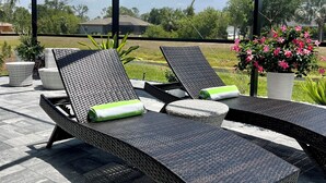 Ein überdachter Außenbereich mit Korlounge-Stühlen und Blick auf eine grüne Landschaft.