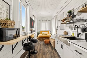 Una cocina compacta con encimera de madera, microondas y lavamanos.