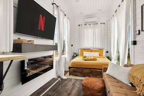 Un dormitorio con cama, televisión, chimenea y ventana.