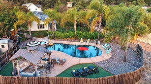 Un jardin avec une piscine, des chaises longues et un espace de jeux pour enfants.