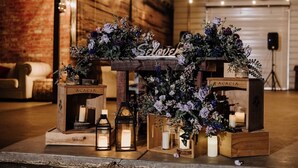 Una mesa de madera rústica con arreglos florales y velas, con la etiqueta 