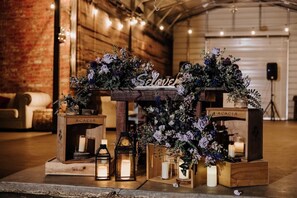 Una mesa de madera rústica con arreglos florales y velas, con la etiqueta 