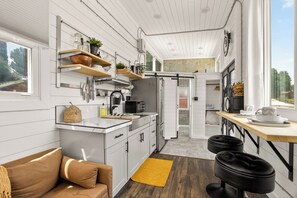 Une cuisine moderne avec des meubles blancs, un plan de travail en bois et une porte coulissante donnant sur un coin repas.