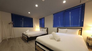 Habitació d'hotel amb dos llits, cadascun amb un llençol i almoades blancs, i un terra de fusta.
