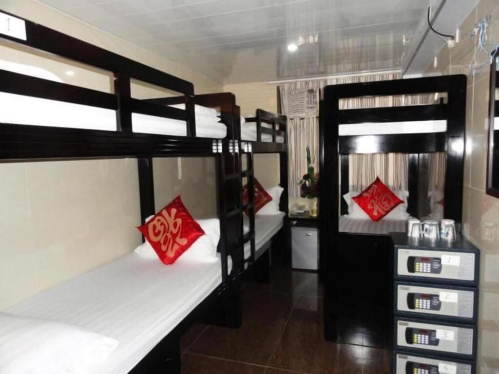 A hotel room with bunk beds, a small desk with a computer, and a minibar.