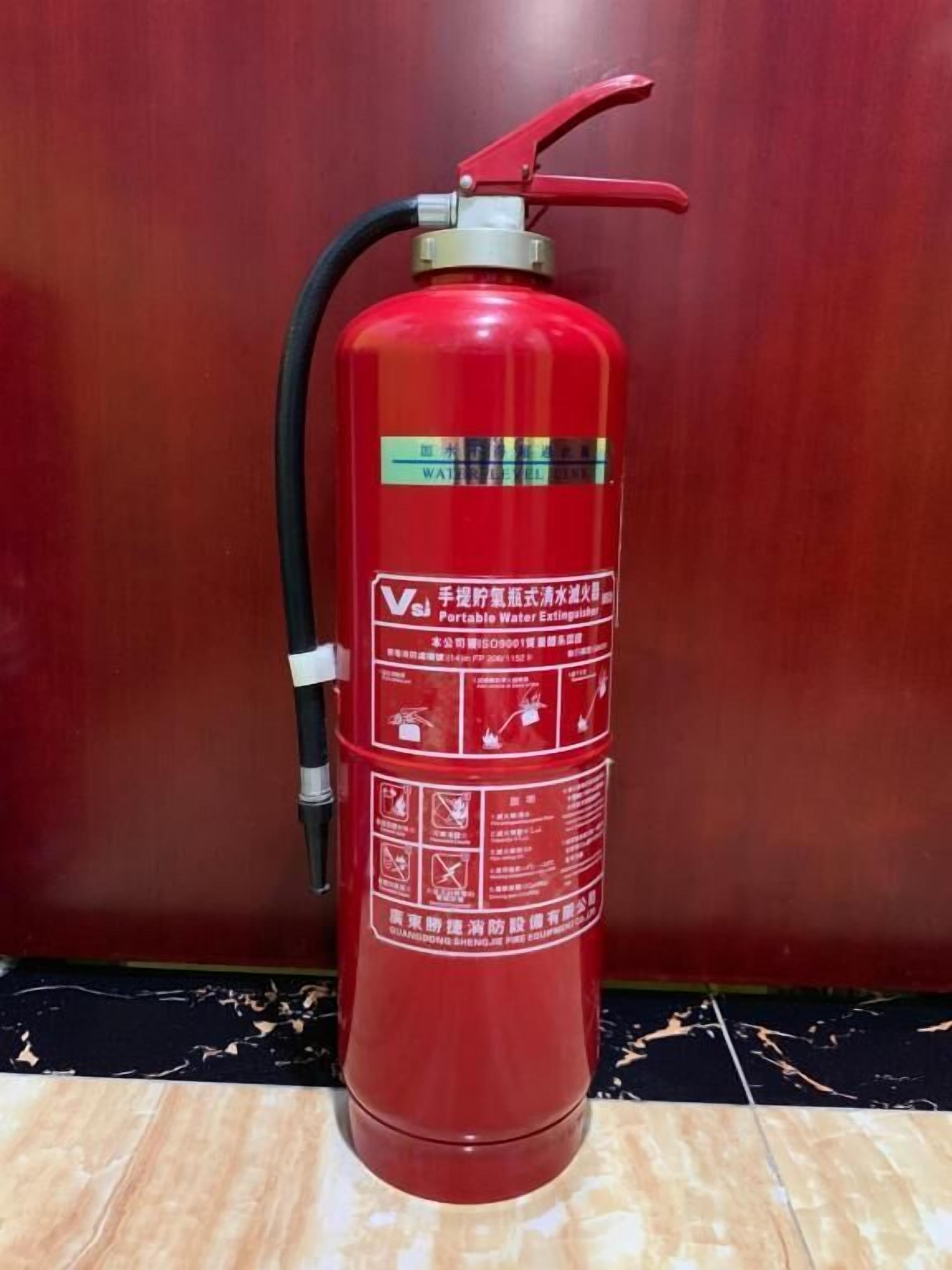 A red portable water extinguisher with safety instructions and a hose.