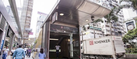 A hotel entrance with a modern design, including a glass facade and a metal staircase.
